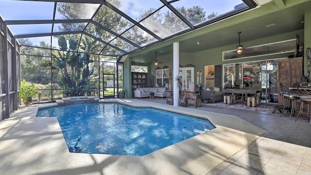 A covered swimming pool with a glass ceiling, surrounded by indoor seating and a patio area. - Luxurious Home w/ Private Pool & Lanai Near Tampa! (Tampa)