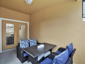An outdoor seating area with a table and chairs, a door with a glass panel, and a textured wall.