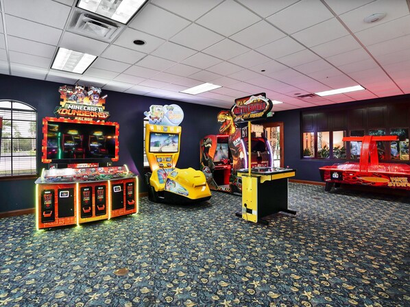 A room with arcade games, a patterned carpet, and a window with a view.