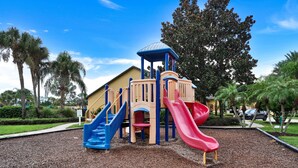 Ein Spielplatz mit Rutsche, Kletterbereich und einem überdachten Spielhäuschen.