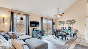 A living room with a sofa, TV, dining table, and chairs. - Cozy Lake Front Condo (Branson)