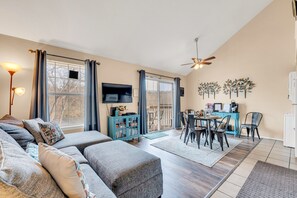 A living room with a sofa, TV, dining table, and chairs.