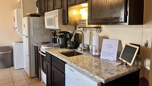 A kitchen with dark wooden cabinets, a white refrigerator, a microwave, a coffee maker, and a sign indicating Fall Creek Unit 43-8. - Cozy Lake Front Condo (Branson)