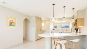 Una cocina moderna con una isla central, iluminación colgante y vistas de la ciudad a través del ventanal.