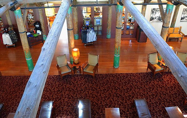 A spacious lobby with wooden flooring, multiple seating areas, and a central area with a table and chairs. - Paradise Inn (Ashford)