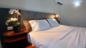 A neatly made bed with white linens, a dark headboard, and a nightstand with a potted orchid. - Aruba private 3 bedroom holiday Villa, pool, walking distance to the beach (Noord)