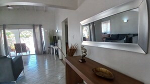 A spacious living area with a large mirror, a wooden console table, and a view of the outdoor patio. - Aruba private 3 bedroom holiday Villa, pool, walking distance to the beach (Noord)