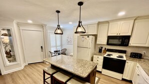 A kitchen with white cabinets, a granite countertop, a black stove, and a microwave. - FREE ACTIVITIES & A gorgeous ocean view unit ready for your enjoyment. (Saint Augustine)