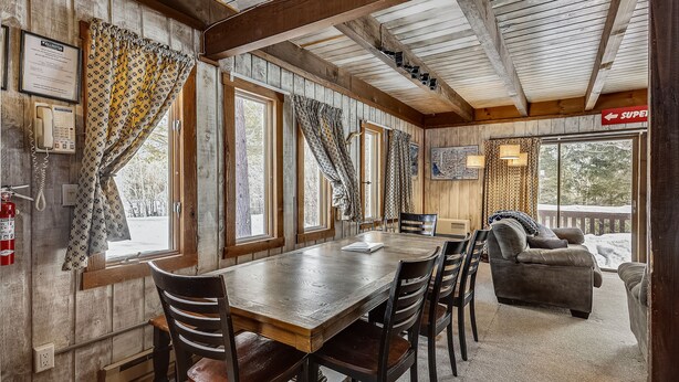A wooden interior with a dining table, chairs, a sofa, and a fireplace.