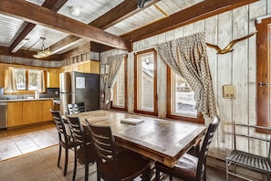 Cozy cabin-style interior with a dining table for four, high ceiling, and large windows.