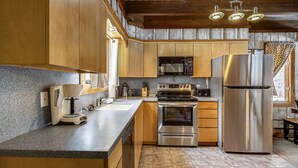 A kitchen with wooden cabinets, a stainless steel refrigerator, a microwave, an oven, and a coffee maker.