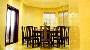 Un comedor con una mesa redonda y sillas, una planta en maceta y una puerta con ventanal.