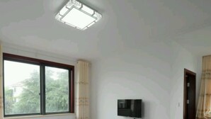 Una habitación de hotel con dos camas, un televisor en la pared y una ventana con cortinas.