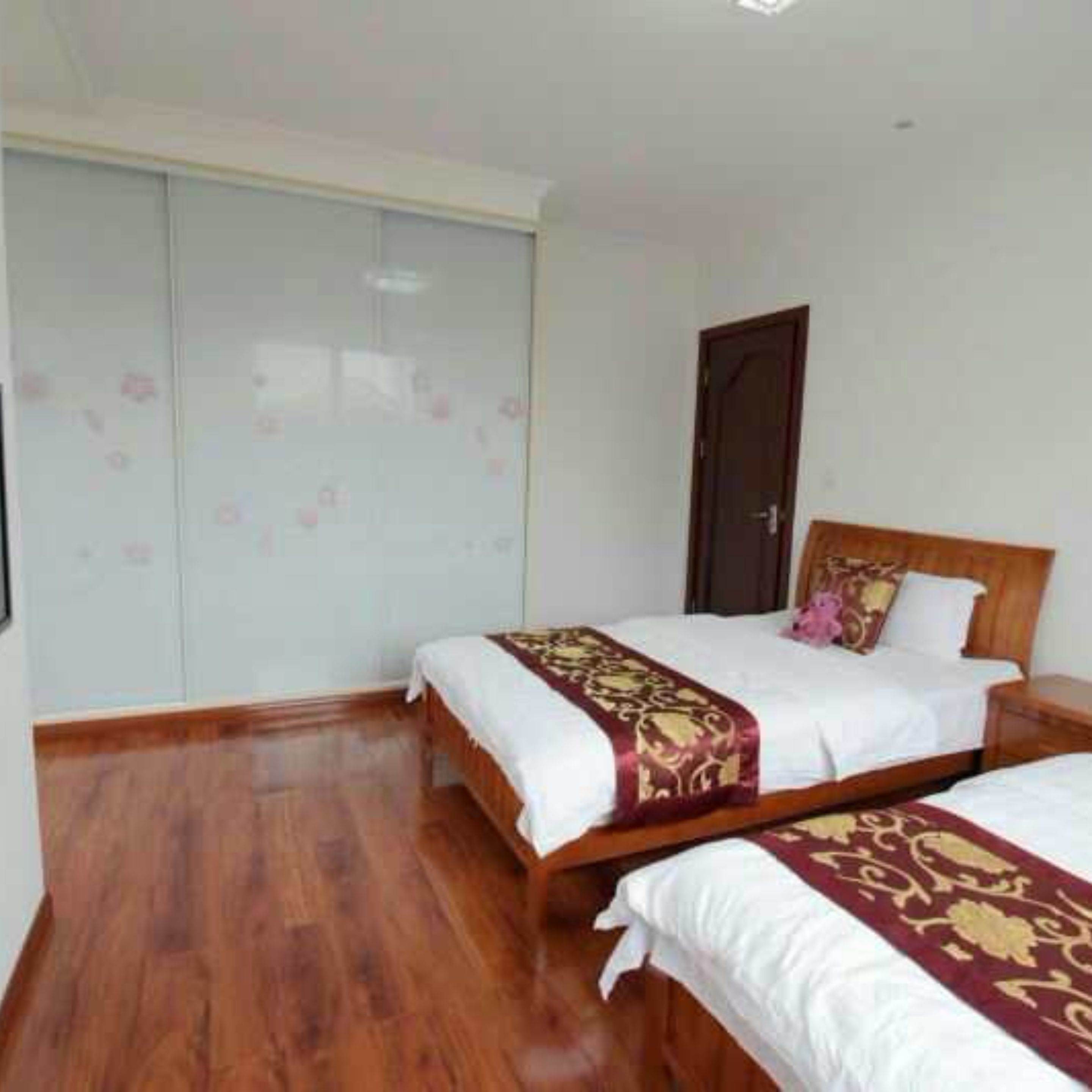 A bedroom with two beds, a wardrobe, and a door.