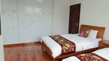 A bedroom with two beds, a wardrobe, and a door.