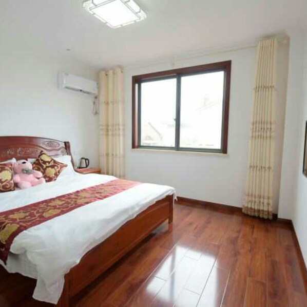 A bedroom with a wooden bed, a window with curtains, and a ceiling light fixture.