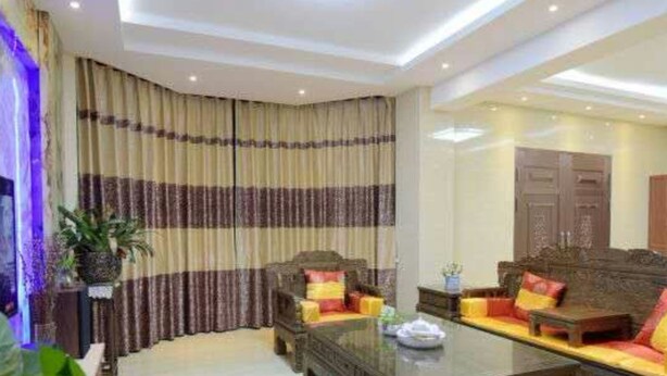 Un salón moderno con una amplia mesa de centro de madera oscura, dos sofás con cojines de colores y un gran ventanal con cortinas a rayas.