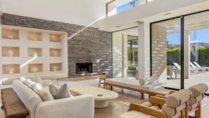 A modern living room with a stone wall, a fireplace, and a view of the outdoors.