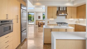 A modern kitchen with wooden cabinets, stainless steel appliances, and a large island.