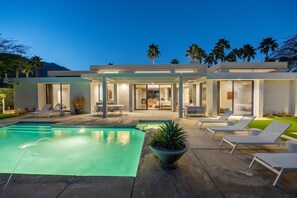 A modern house with a swimming pool, outdoor seating, and a well-lit patio area. - Pet-Friendly Gated Home near Downtown (Palm Springs)