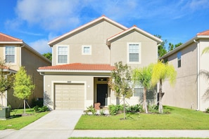 A two-story residential building with a garage, a front lawn, and a clear sky.