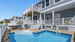Una propiedad residencial con piscina, un porche cubierto y una casa de dos pisos con balcón.