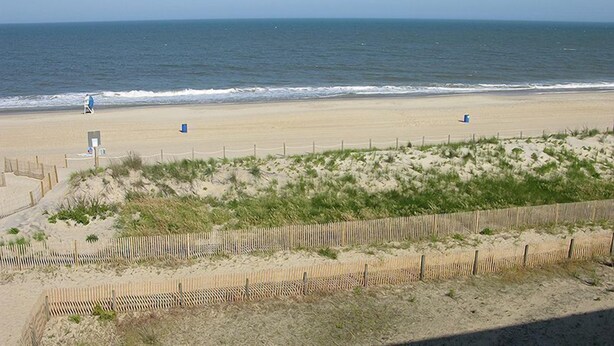 A beach with a wooden fence, a lifeguard tower, and a clear view of the ocean. - Even Keel 404-Oceanfront 75th St, Elev, W/D, AC (Ocean City)