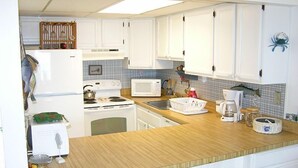 A compact kitchen with white cabinets, a microwave, a stove, and a sink. - Even Keel 404-Oceanfront 75th St, Elev, W/D, AC (Ocean City)