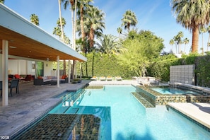 A modern outdoor pool area with a covered seating area, lounge chairs, and a stone-tiled pool. - Mid-Century Home with Theater and Spa (Palm Springs)