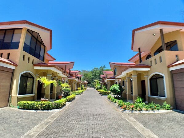 A corridor lined with uniform buildings, each with a red roof and beige walls, leading to a central point.