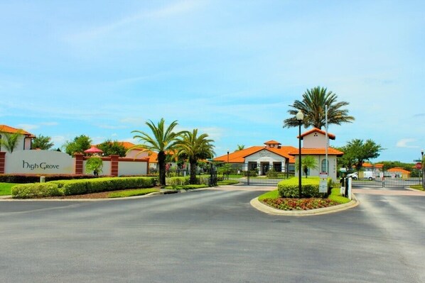 A gated community with a central road, palm trees, and a building with a sign reading "High Grove."