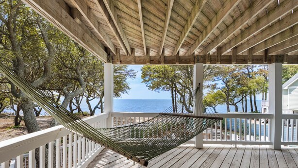 A hammock on a wooden deck with a view of the ocean and trees. - Sound & Sol: Soundfront, Private Pool, Hot Tub (Corolla)