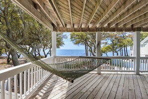 A hammock on a wooden deck with a view of the ocean and trees. - Sound & Sol: Soundfront, Private Pool, Hot Tub (Corolla)