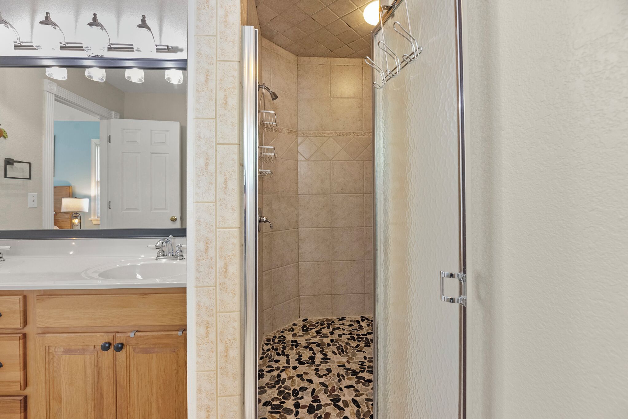 Een badkamer met een douche, een wastafel en een spiegel.