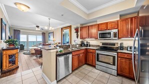 A modern kitchen with wooden cabinets, stainless steel appliances, and a central island. - Gulf Shores Condo with Gulf Views | Lazy River, Pools, and Hot Tub | Sleeps 6 (Gulf Shores)