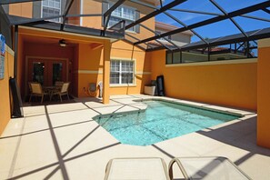 Una piscina interior con techo de vidrio, rodeada por un patio luminoso con sillones de descanso.