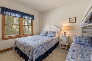 Une chambre avec deux lits, une table de chevet, une lampe et une fenêtre avec des stores.