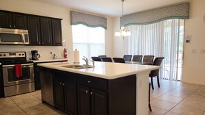 A modern kitchen with dark cabinets, stainless steel appliances, and a central island. - Luxurious Home with Private Pool Upstairs  Games Room. 928 (Davenport)