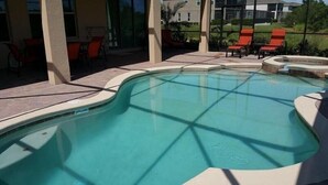 A swimming pool with a curved edge, surrounded by a patio area with chairs and a view of a residential neighborhood. - Luxurious Home with Private Pool Upstairs  Games Room. 928 (Davenport)