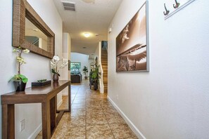 A hallway with a wooden console table, a mirror, and a framed picture on the wall.