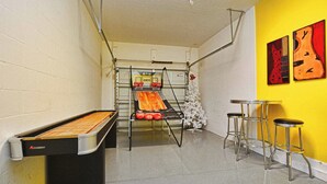 Une table de billard avec un filet, un panier de basket et trois tabourets.