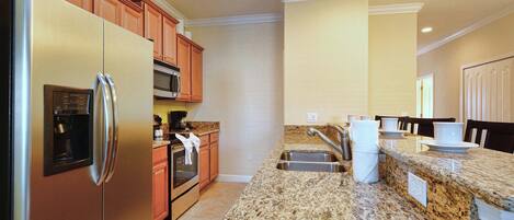 A kitchen with granite countertops, stainless steel appliances, wooden cabinets, and a built-in microwave.