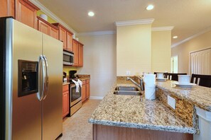 A kitchen with granite countertops, stainless steel appliances, wooden cabinets, and a built-in microwave.