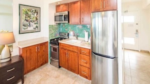 A modern kitchen with wooden cabinets, stainless steel appliances, and a tiled backsplash.