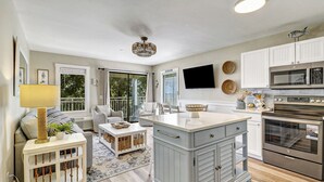 A modern kitchen with white cabinetry, a large island, and stainless steel appliances. - Gorgeous Beachfront Retreat! Heated Oceanfront Pool (Hilton Head Island)