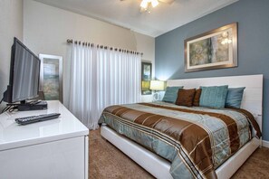 A bedroom with a bed, a TV on a desk, a lamp, and a painting on the wall. - Minutes to Disney | Private Pool, Resort Amenities & BBQ Grill - 1600ST (Kissimmee)