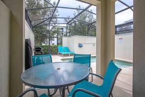 A covered outdoor area with a glass table and chairs, a pool, and lounge chairs. - Minutes to Disney | Private Pool, Resort Amenities & BBQ Grill - 1600ST (Kissimmee)