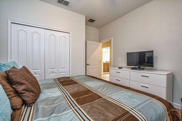 A bedroom with a bed, a TV on a dresser, and a closet. - Minutes to Disney | Private Pool, Resort Amenities & BBQ Grill - 1600ST (Kissimmee)