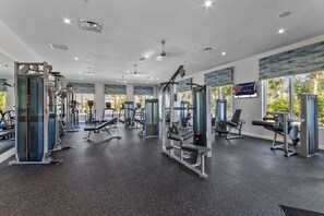A gym with various exercise machines, large windows, and a ceiling with recessed lighting. - Minutes to Disney | Private Pool, Resort Amenities & BBQ Grill - 1600ST (Kissimmee)