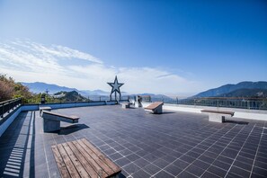 A rooftop terrace with a star-shaped monument, benches, and a railing overlooking mountains. - Star Villa Cingjing (Ren'ai)
